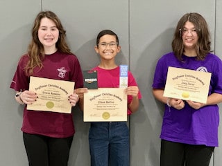Three students proudly holding achievement certificates