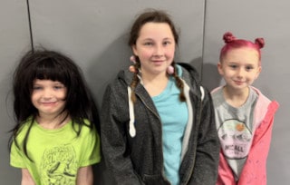 Two Mayflower students and an adult posing together indoors