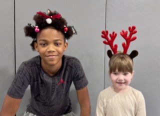 Two Mayflower students wearing festive holiday headwear