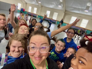 Students and a teacher gathering for a joyful group selfie