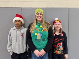 An adult and two Mayflower students posing in holiday clothing
