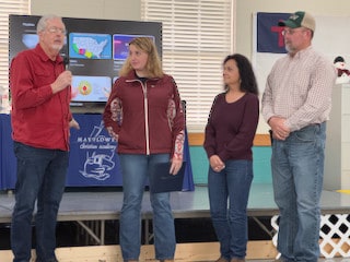 Four adult guest speakers presenting in front of a classroom display